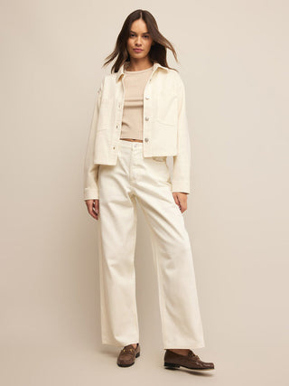 an off white cream cropped denim jacket with silver buttons worn with cream pants