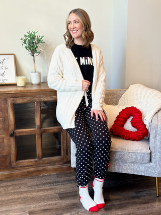 a soft warm cable knit cardigan sweater in a cream color worn over black pajamas