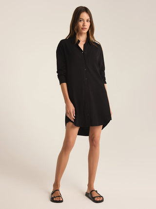 a sophisticated black linen shirt dress with long sleeves and button front design worn with black sandals