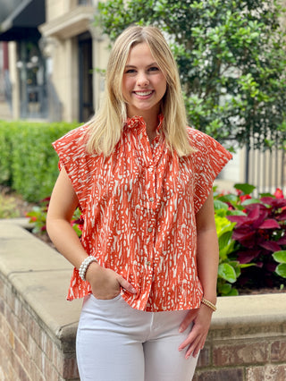 an orange printed blouse with a ruffled split neck and button down front